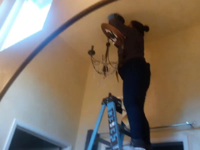 Electrician installing a chandelier in a Lawrence residence